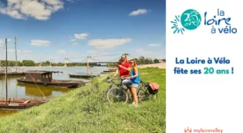 photo d'un couple de cyclistes en bord de Loire l'été avec des bateaux en bois