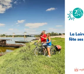 photo d'un couple de cyclistes en bord de Loire l'été avec des bateaux en bois