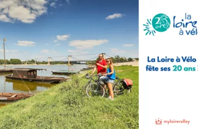 photo d'un couple de cyclistes en bord de Loire l'été avec des bateaux en bois