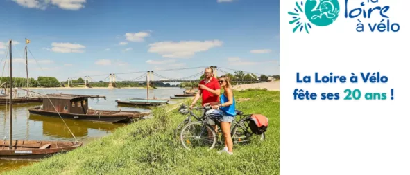 photo d'un couple de cyclistes en bord de Loire l'été avec des bateaux en bois